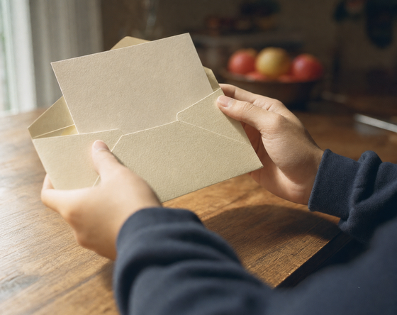 Hands opening an acceptance letter on a kitchen table